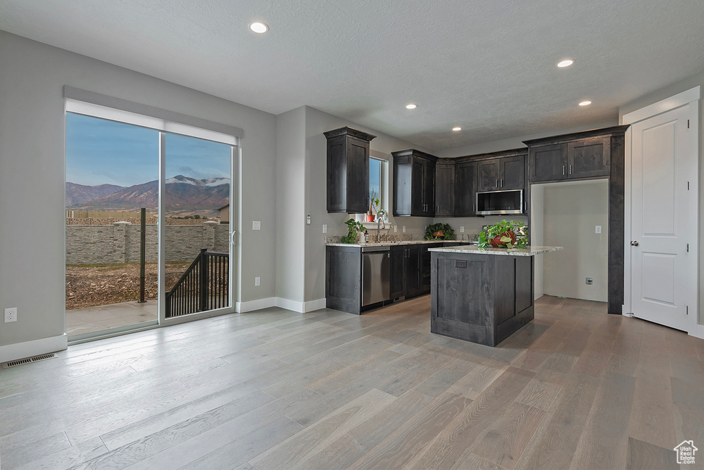 Kitchen with a textured ceiling, a center island, stainless steel appliances, a mountain view, and light hardwood / wood-style flooring