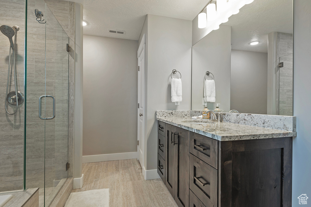 Bathroom featuring vanity, a textured ceiling, walk in shower, and hardwood / wood-style flooring