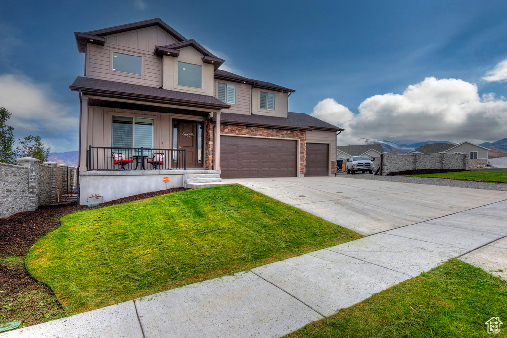 View of front of property with a porch, a front lawn, and a garage