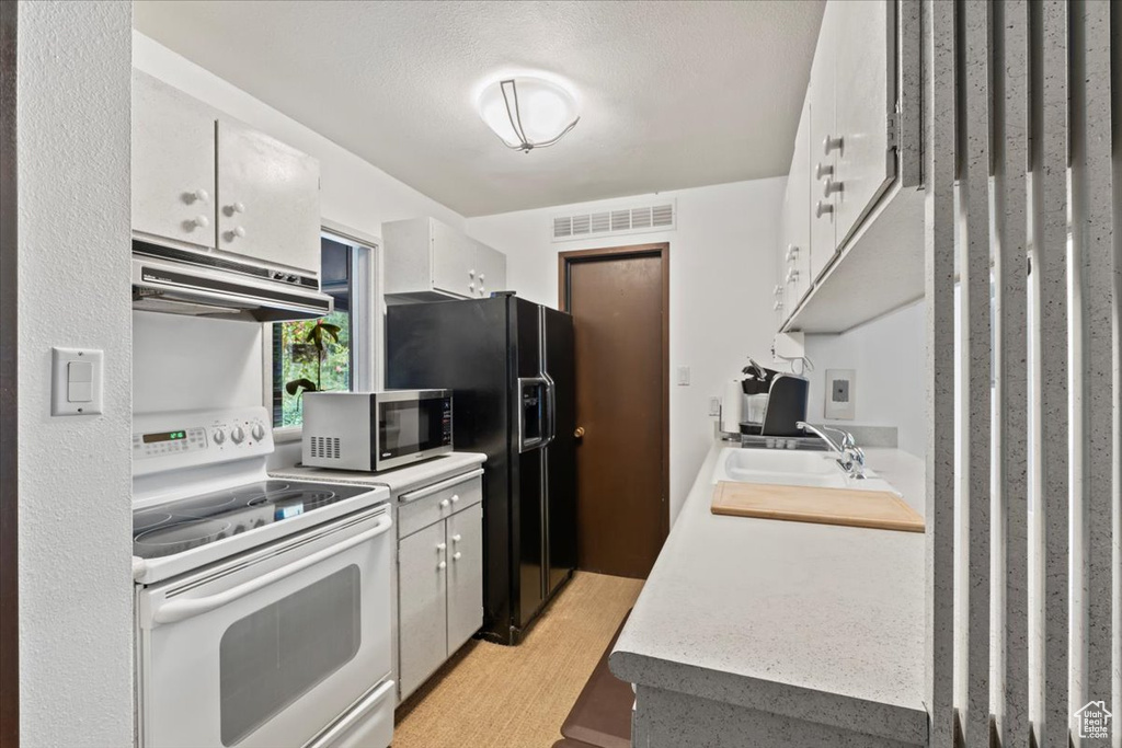 Kitchen featuring sink, a textured ceiling, black refrigerator with ice dispenser, white range with electric cooktop, and white cabinets