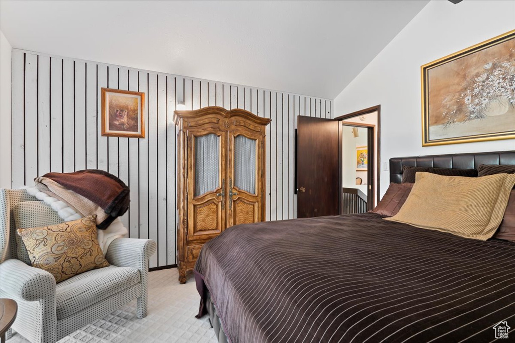 Carpeted bedroom with wooden walls and vaulted ceiling