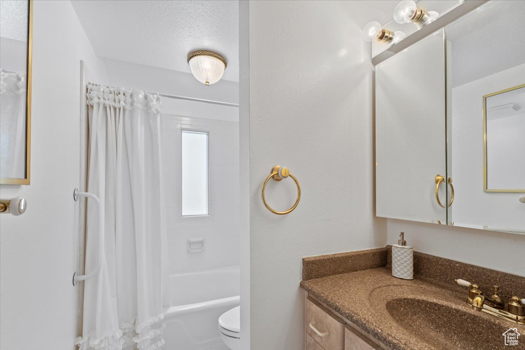 Full bathroom with toilet, vanity, and shower / bath combination with curtain