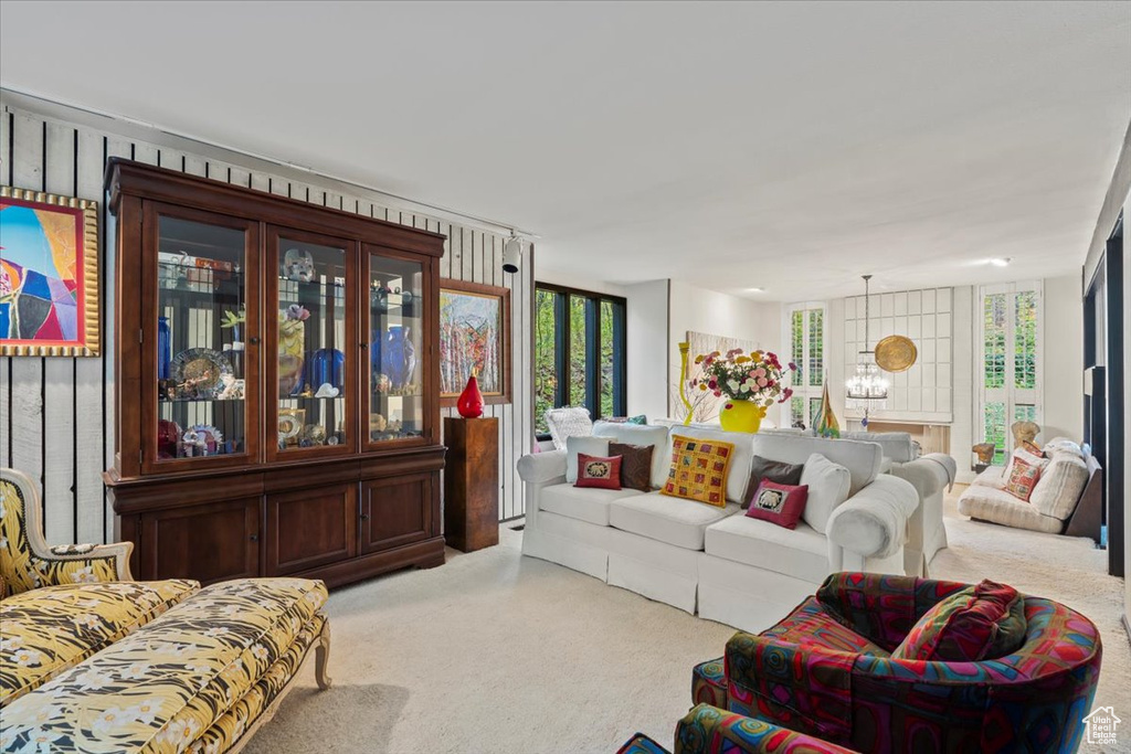 Carpeted living room featuring an inviting chandelier and a wealth of natural light