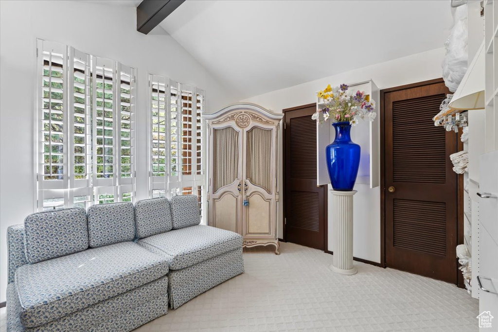 Interior space with decorative columns, vaulted ceiling with beams, and light carpet