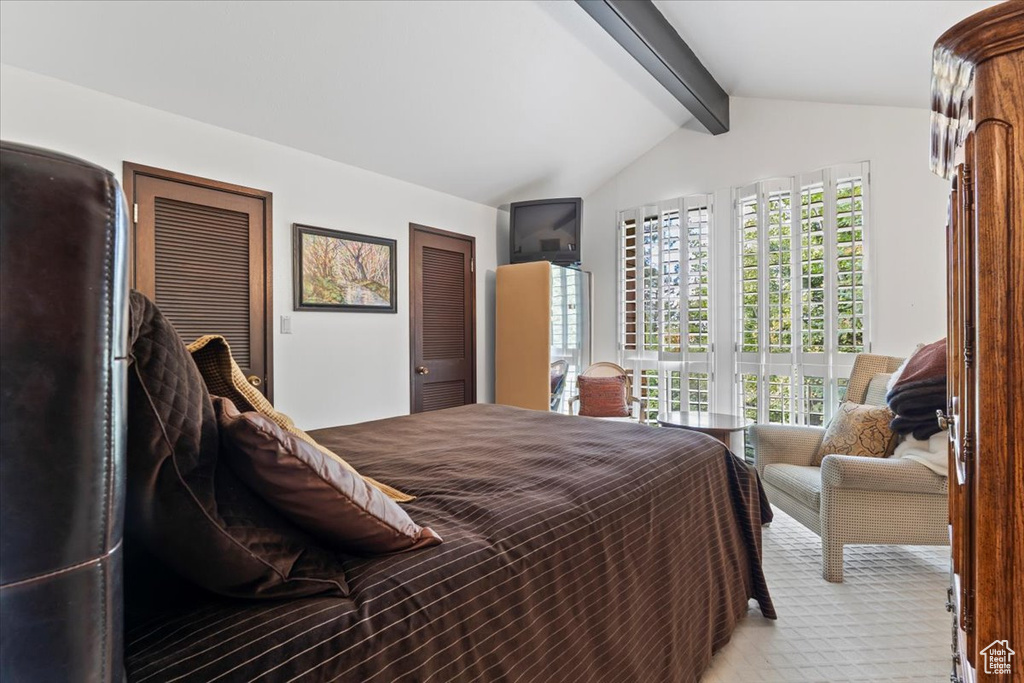 Bedroom with vaulted ceiling with beams, multiple windows, and light carpet