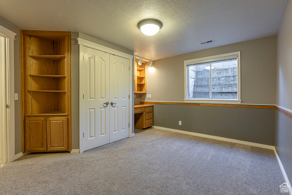 Unfurnished bedroom featuring a closet, a textured ceiling, and light colored carpet