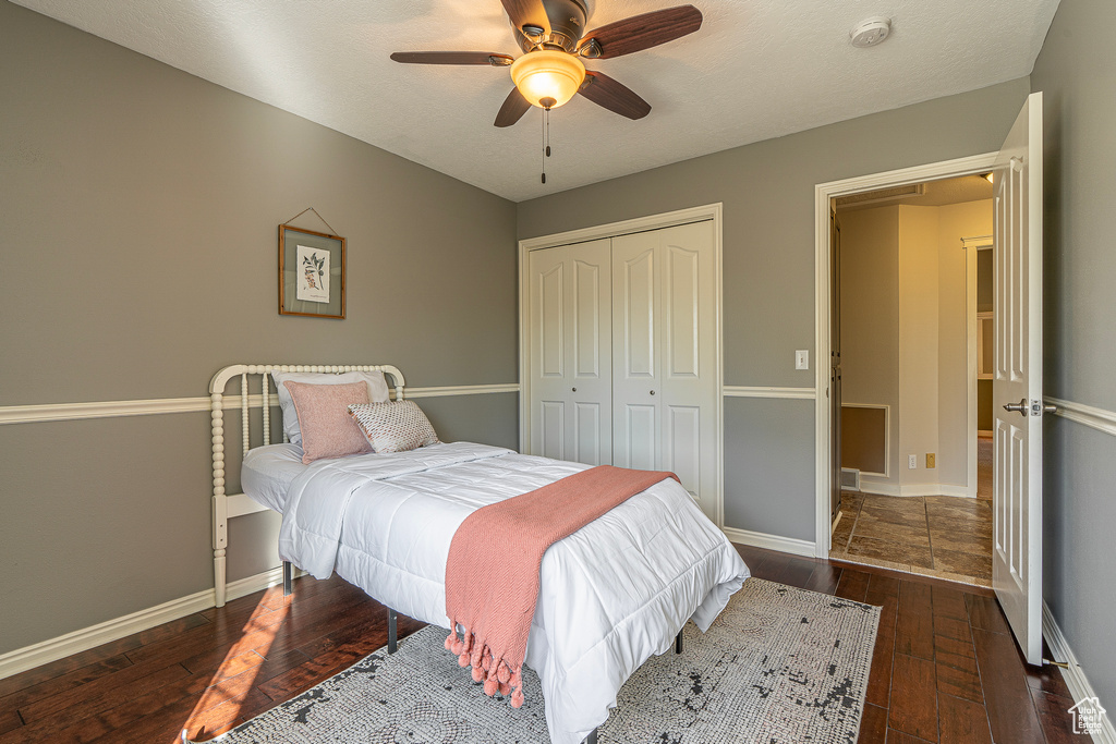 Bedroom featuring ceiling fan, a textured ceiling, a closet, and dark hardwood / wood-style flooring