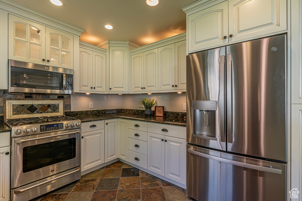 Kitchen featuring appliances with stainless steel finishes and dark stone counters