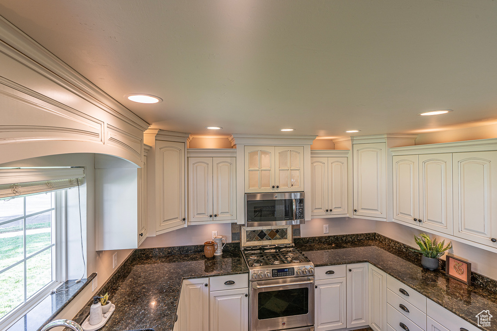 Kitchen featuring appliances with stainless steel finishes, white cabinets, and dark stone countertops