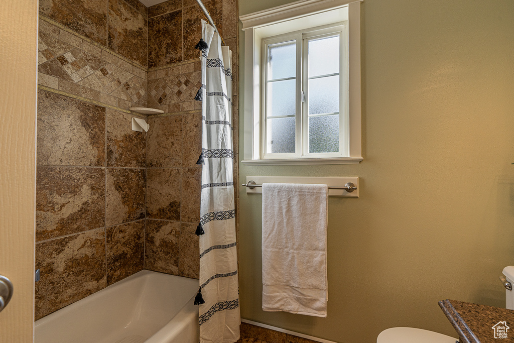 Full bathroom featuring toilet, shower / bath combo, and vanity