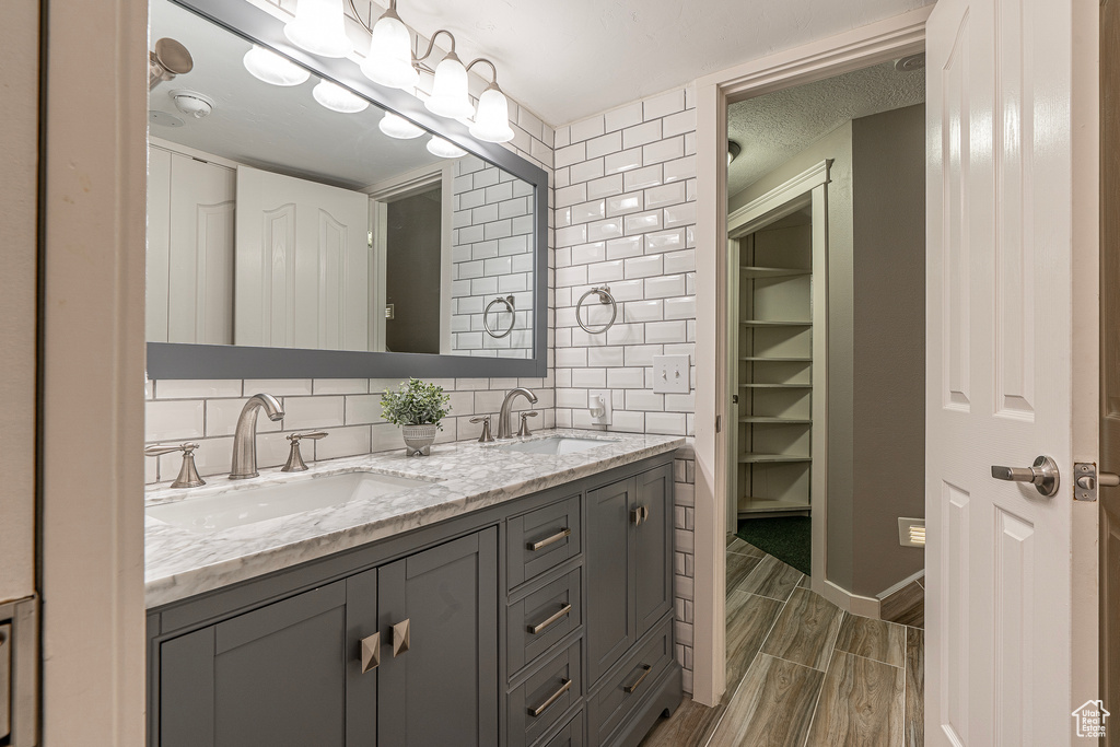 Bathroom featuring vanity, tasteful backsplash, wood-type flooring, and a textured ceiling