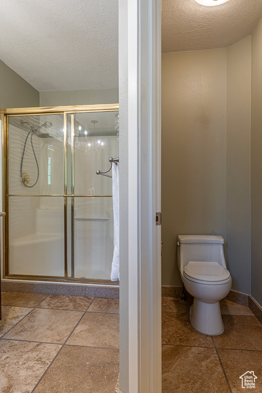 Bathroom featuring toilet, a textured ceiling, and a shower with shower door