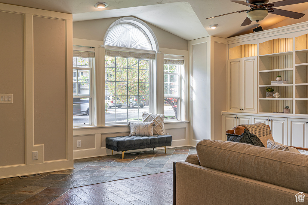 Living area with ceiling fan, a healthy amount of sunlight, lofted ceiling, and dark hardwood / wood-style floors