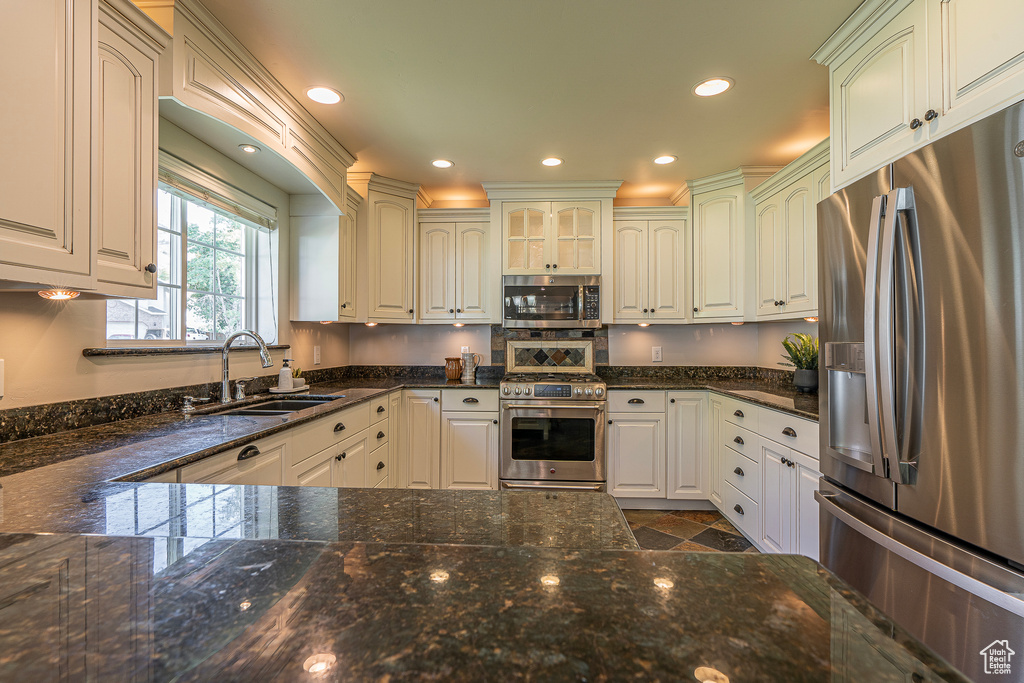 Kitchen featuring sink, appliances with stainless steel finishes, white cabinets, and dark stone countertops