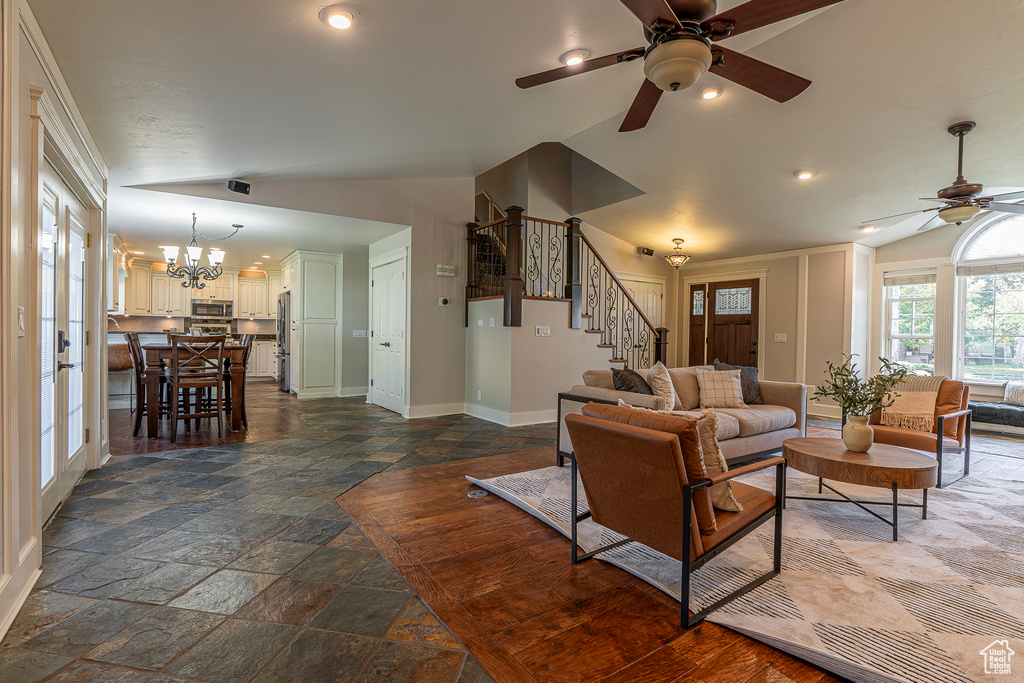 Living room with lofted ceiling and ceiling fan with notable chandelier