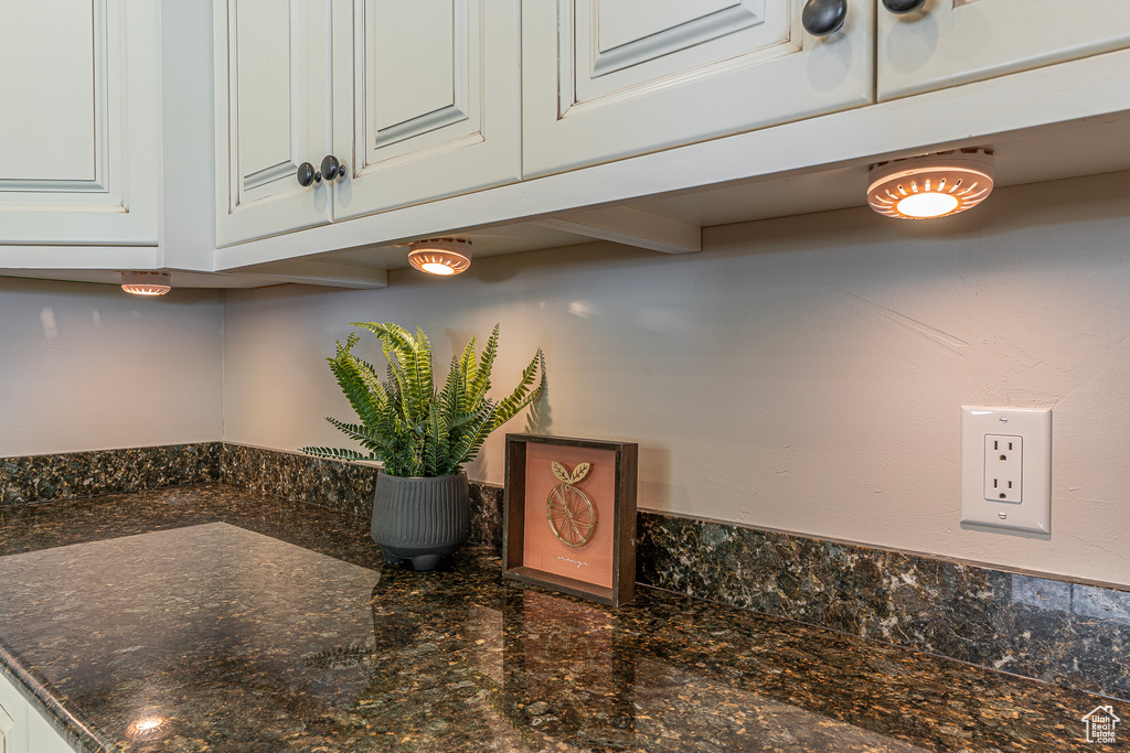 Room details featuring white cabinetry and dark stone countertops