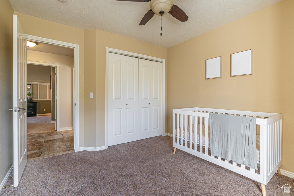 Unfurnished bedroom with a closet, ceiling fan, a textured ceiling, and carpet floors