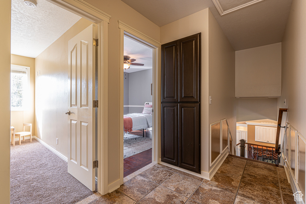 Hall featuring light carpet and a textured ceiling