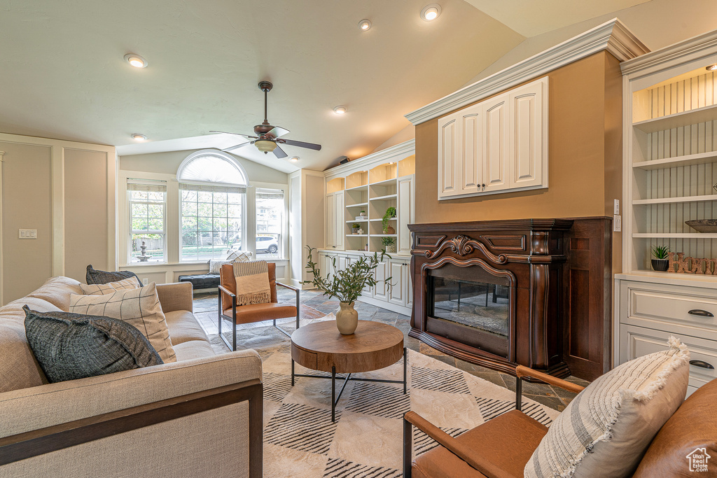 Living room featuring ceiling fan, vaulted ceiling, and built in shelves