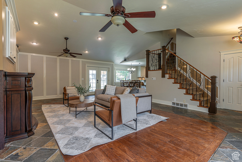 Living room with dark hardwood / wood-style flooring, french doors, ceiling fan with notable chandelier, and vaulted ceiling