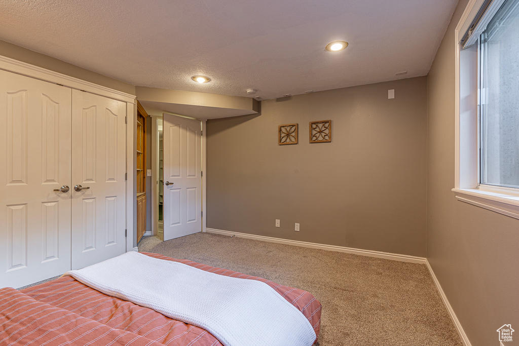 Bedroom with carpet, a textured ceiling, and a closet