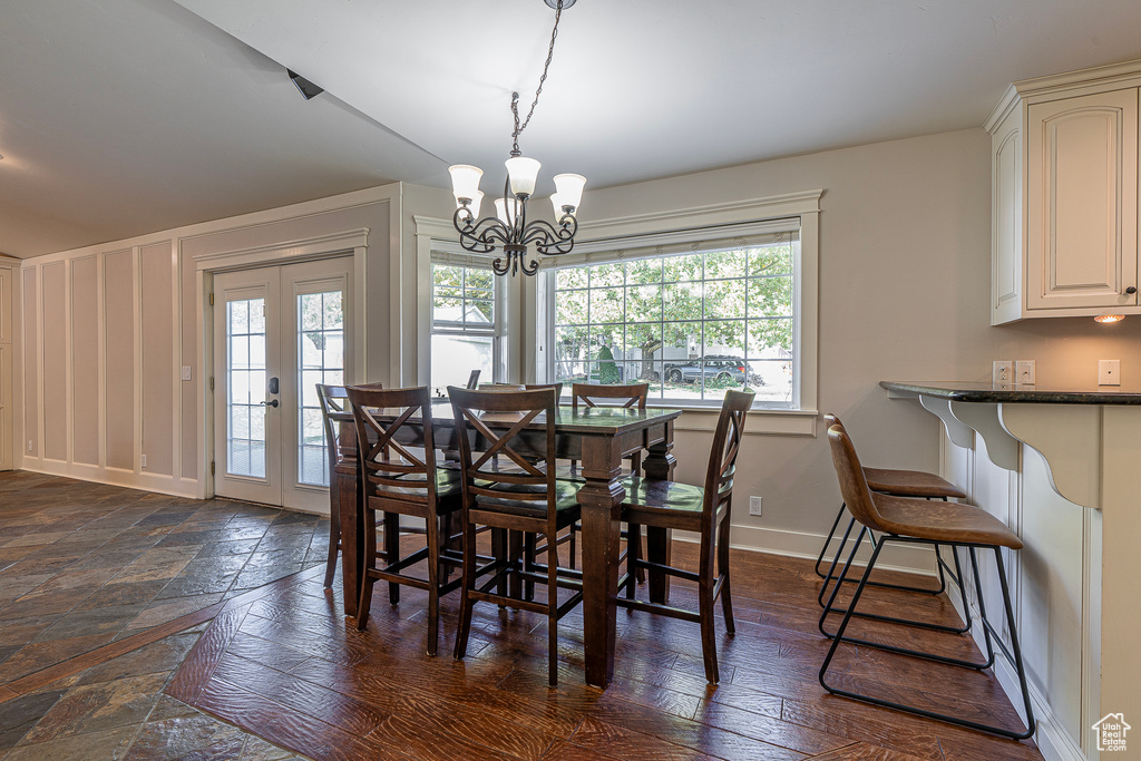 Dining room featuring french doors, dark hardwood / wood-style floors, a healthy amount of sunlight, and a chandelier