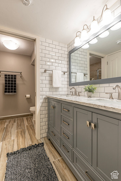 Bathroom with vanity, toilet, wood-type flooring, and backsplash