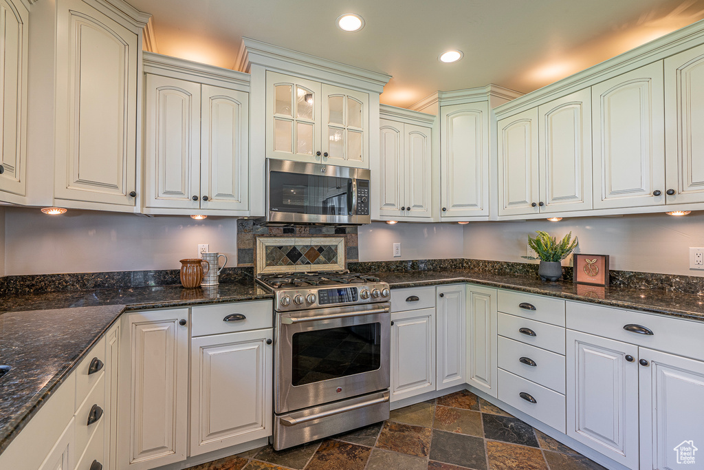 Kitchen featuring stainless steel appliances, dark stone counters, and white cabinets