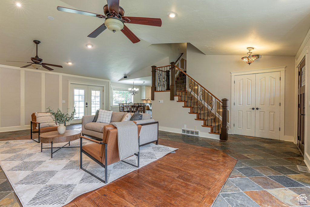 Living room featuring french doors, vaulted ceiling, crown molding, and ceiling fan with notable chandelier