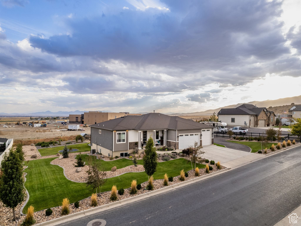 View of front of property with a mountain view, a front yard, and a garage