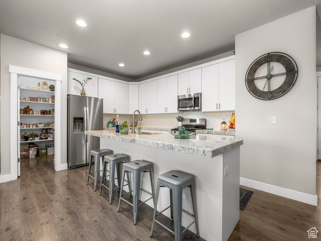 Kitchen with appliances with stainless steel finishes, white cabinetry, sink, and dark wood-type flooring