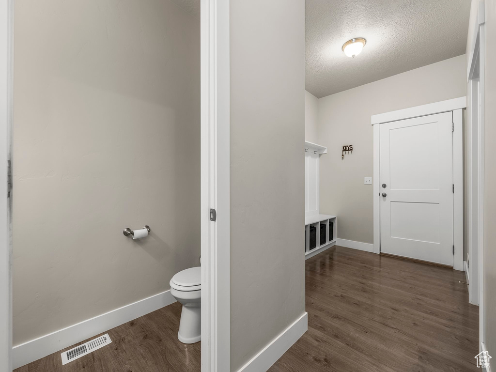 Bathroom with toilet, a textured ceiling, and hardwood / wood-style floors