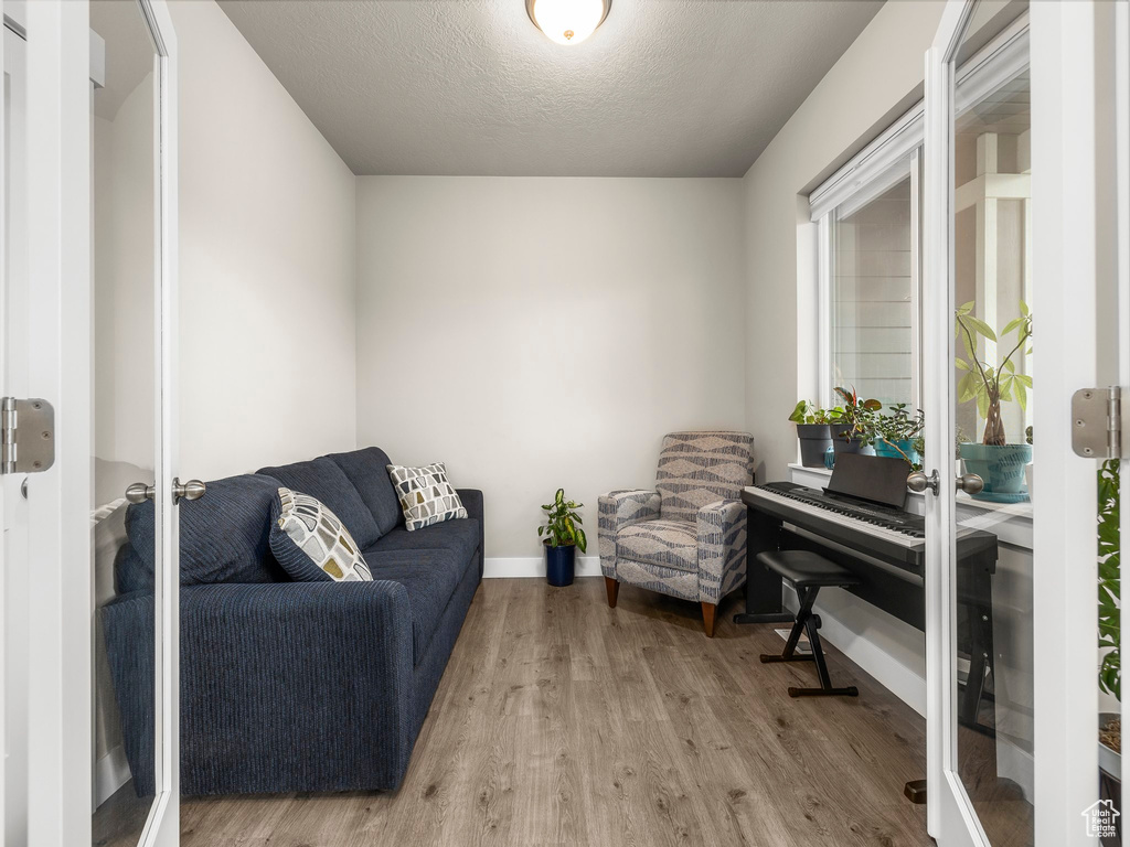 Sitting room with french doors, a textured ceiling, and light hardwood / wood-style flooring