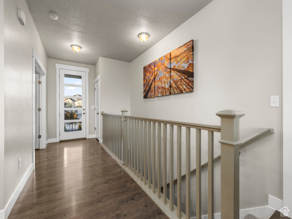 Hallway with a textured ceiling and dark hardwood / wood-style floors