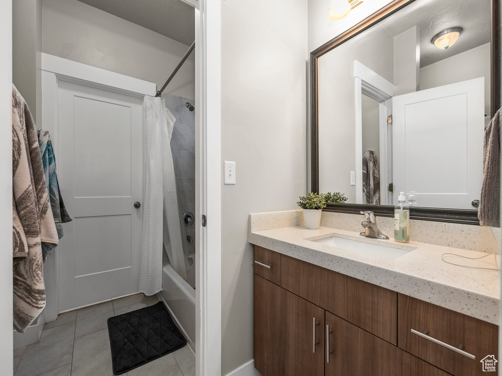 Bathroom with vanity, shower / tub combo, and tile patterned flooring