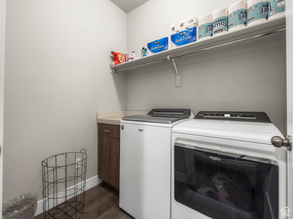 Washroom with washing machine and clothes dryer, cabinets, and dark hardwood / wood-style flooring