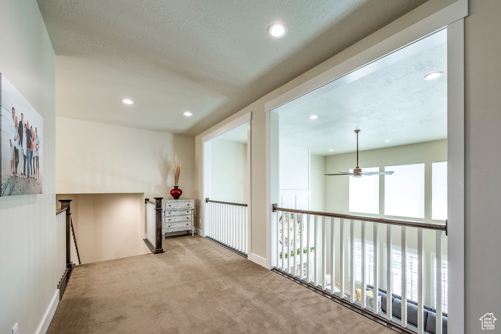 Corridor with a textured ceiling and light colored carpet