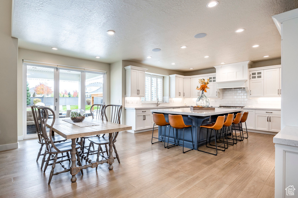 Dining room featuring sink, a textured ceiling, and light hardwood / wood-style flooring