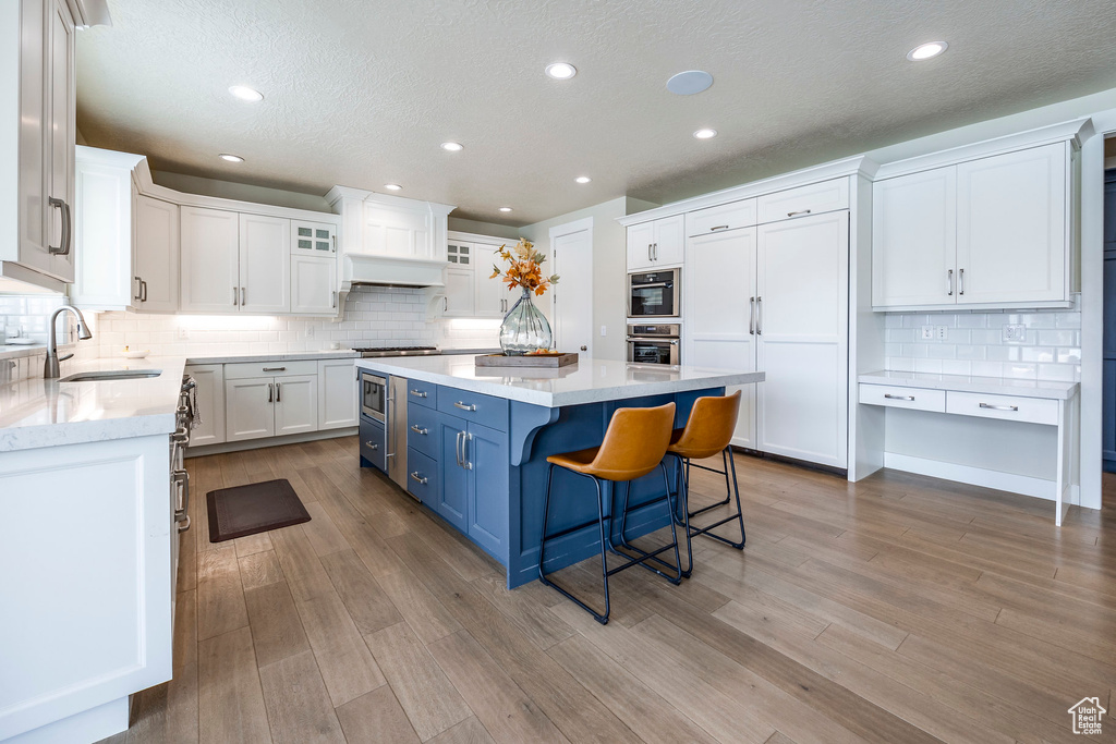 Kitchen featuring light hardwood / wood-style floors, sink, a kitchen island, and white cabinets