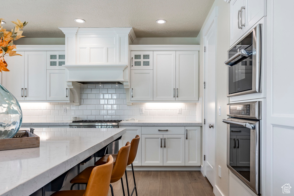 Kitchen featuring hardwood / wood-style floors, white cabinets, and stainless steel appliances