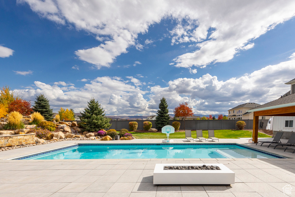 View of swimming pool with a yard, a patio area, and a fire pit