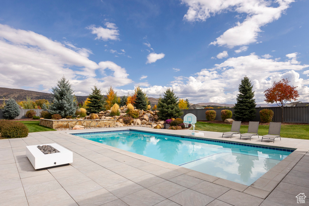 View of pool featuring a patio area, a lawn, a mountain view, and a fire pit