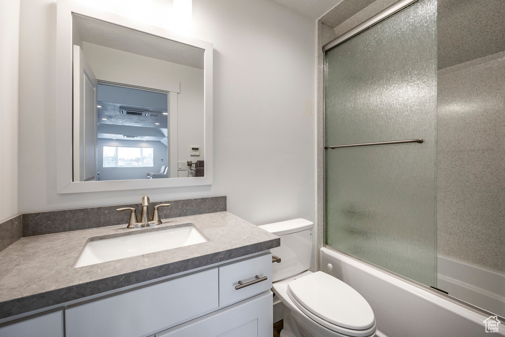 Full bathroom with toilet, combined bath / shower with glass door, and vanity