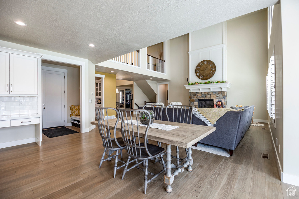 Dining space with a stone fireplace, a textured ceiling, and light wood-type flooring