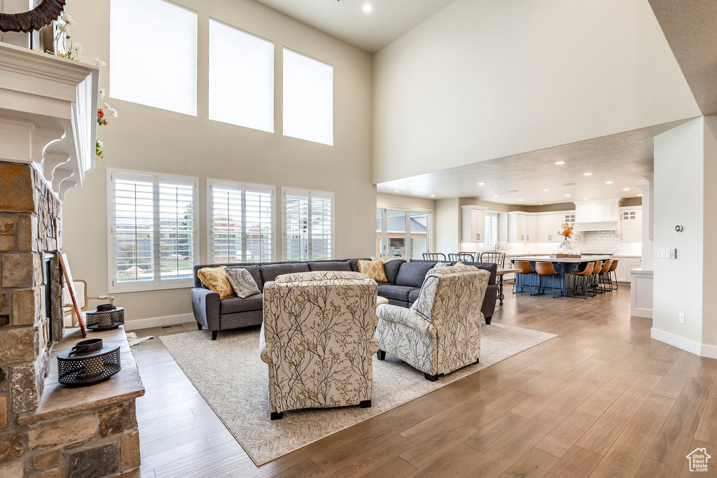 Living room with a towering ceiling, light hardwood / wood-style flooring, and a fireplace