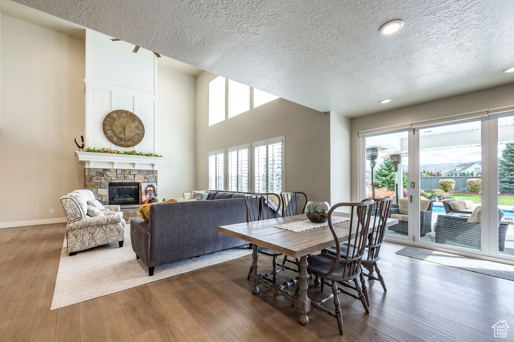 Dining area with a stone fireplace, a textured ceiling, a healthy amount of sunlight, and dark hardwood / wood-style flooring