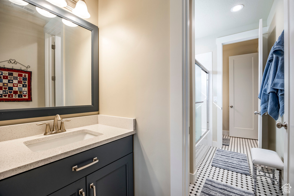 Bathroom with vanity, enclosed tub / shower combo, and tile patterned flooring