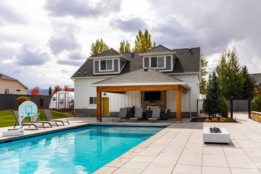 Back of property featuring a patio area, a storage unit, a fenced in pool, and outdoor lounge area