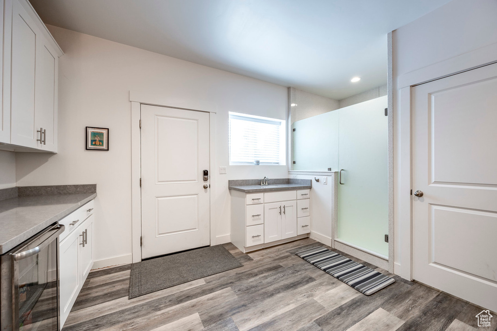 Interior space with vanity, a shower with door, hardwood / wood-style floors, and beverage cooler