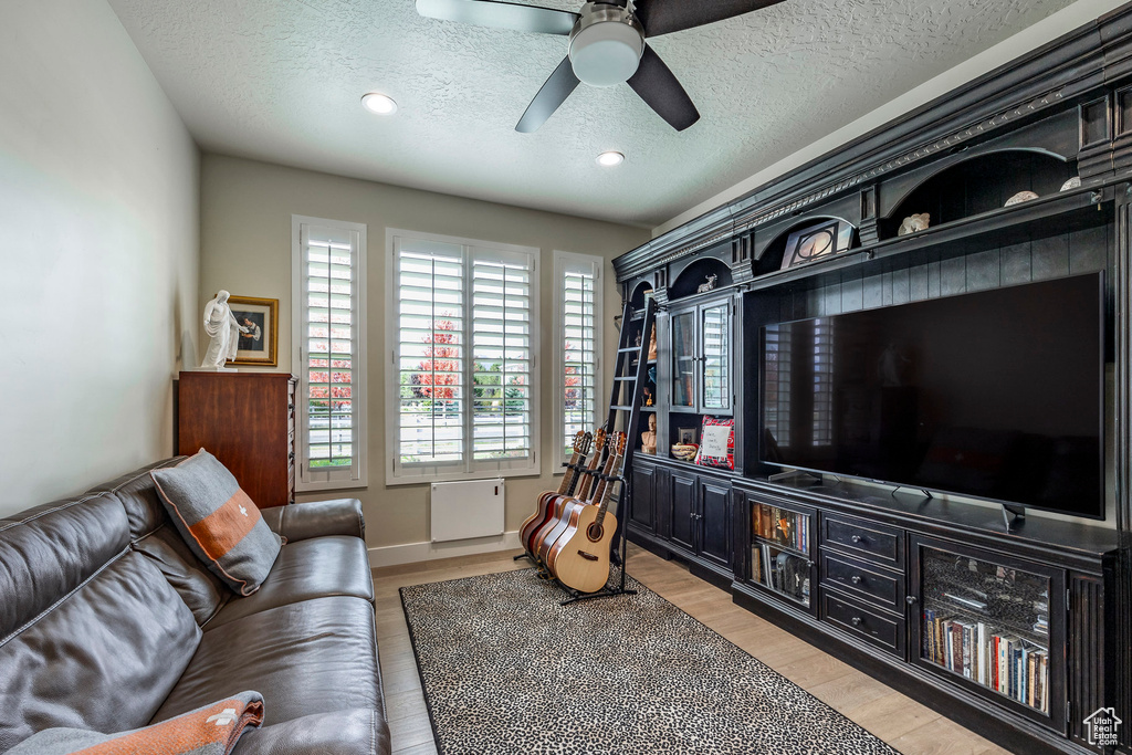 Living room featuring a textured ceiling, light hardwood / wood-style floors, and ceiling fan